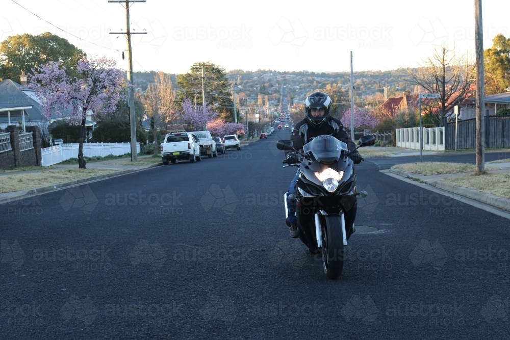 Man riding motorbike on a suburban street - Australian Stock Image