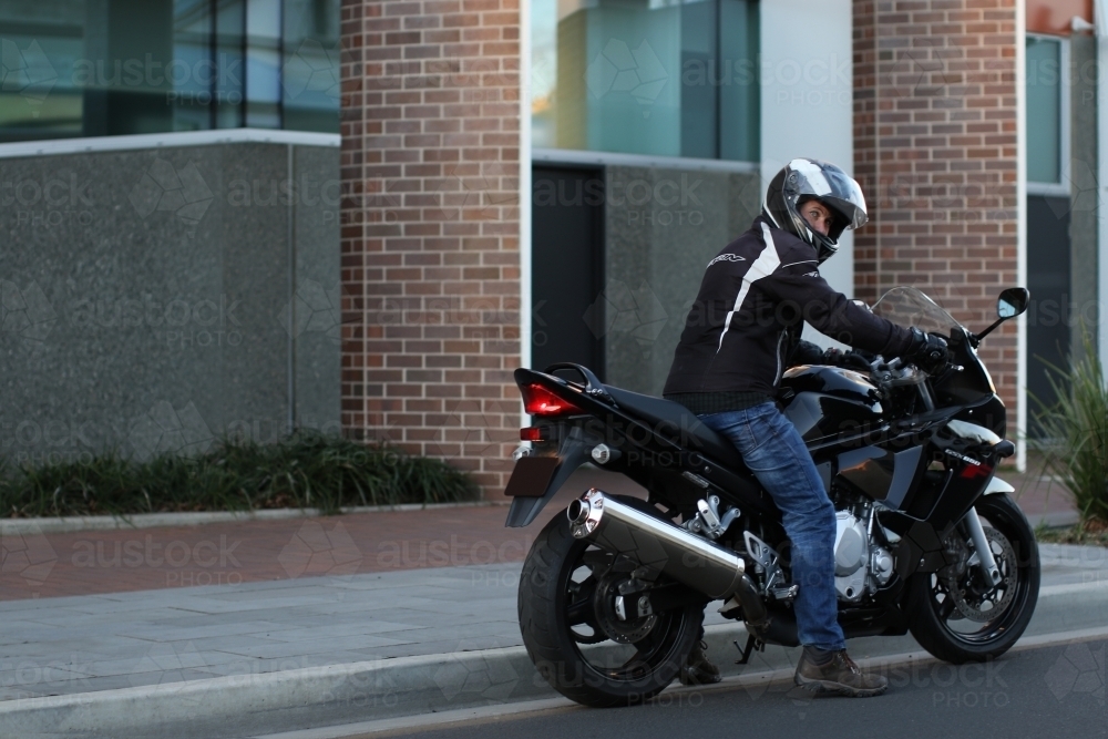 Man riding motorbike on a suburban street - Australian Stock Image