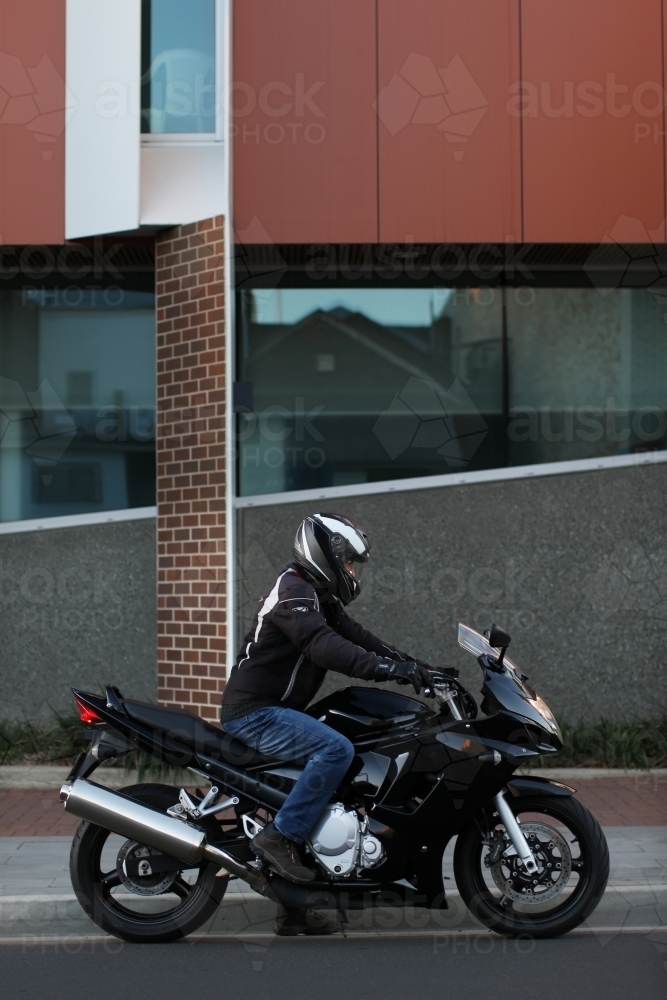 Man riding motorbike on a suburban street - Australian Stock Image