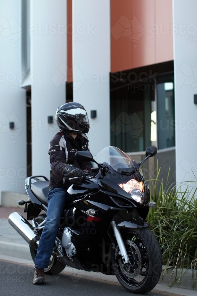 Man riding motorbike on a suburban street - Australian Stock Image