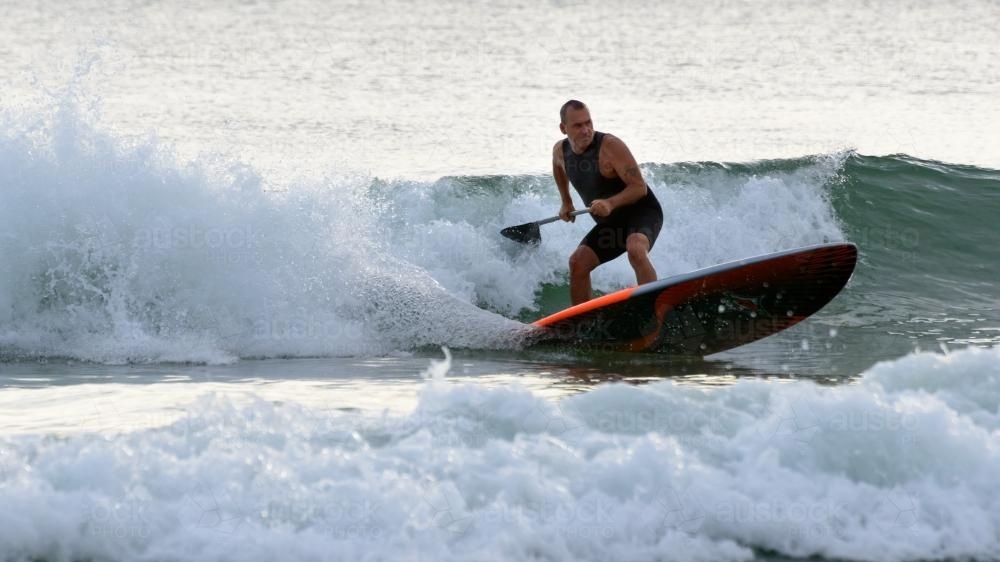 Man riding waves on paddleboard - Australian Stock Image