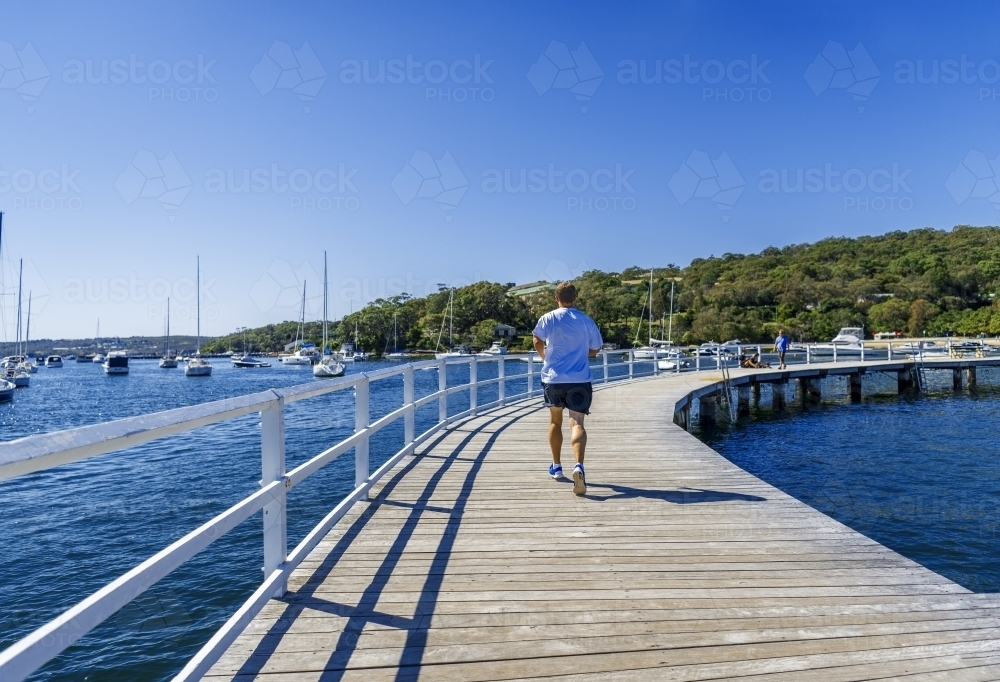 Man running at Balmoral Beach jetty - Australian Stock Image