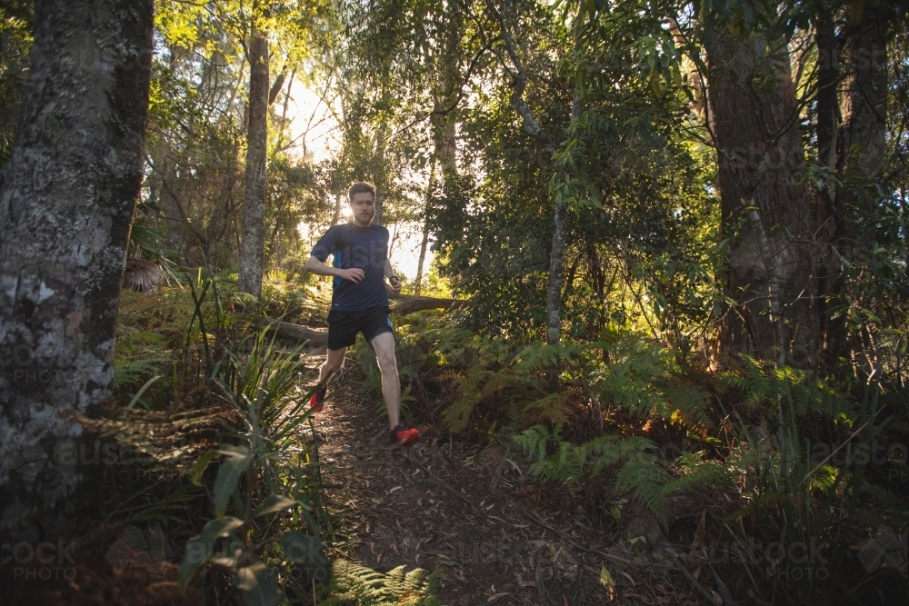 Man running on dirt path in bushland - Australian Stock Image