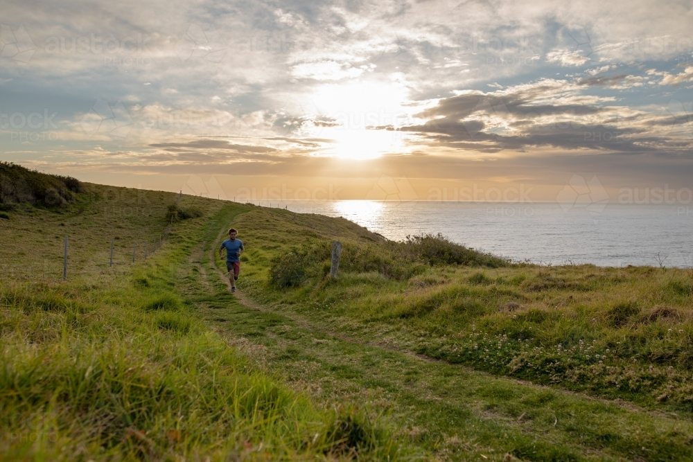 Man Running on winding lush, grassy field on the Coastside - Australian Stock Image