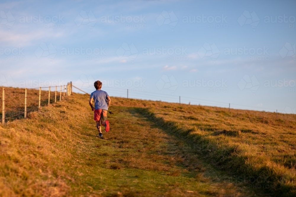Man Running Uphill Alone on Paddock - Australian Stock Image