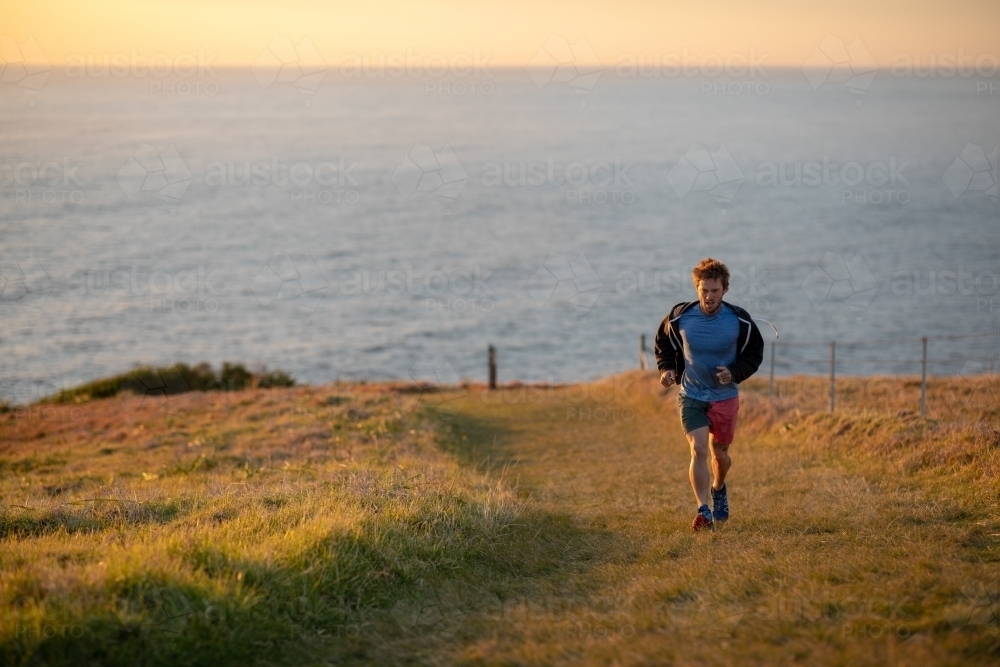Man Running Uphill Away from Ocean - Australian Stock Image