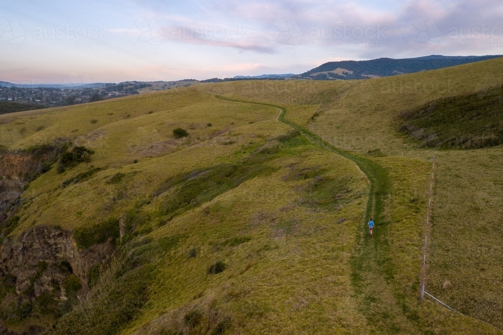 Man Running Uphill on Mountainside - Australian Stock Image
