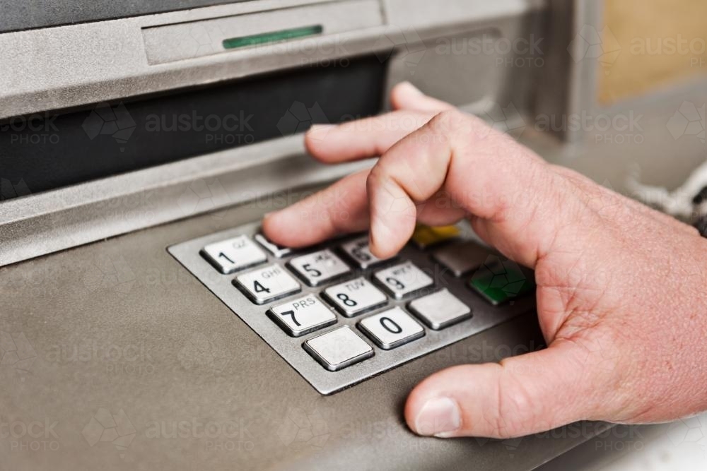 Man's hand at an ATM, entering PIN - Australian Stock Image