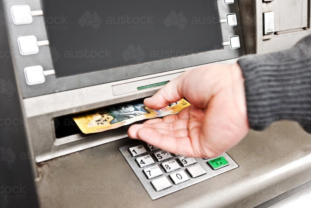 Man's hand at the ATM, with money - Australian Stock Image