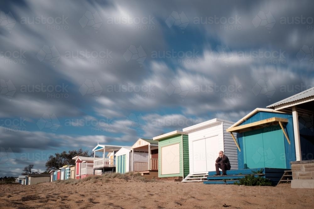 Man seated on Steps of Bathing Box, Mount Martha Beach - Australian Stock Image