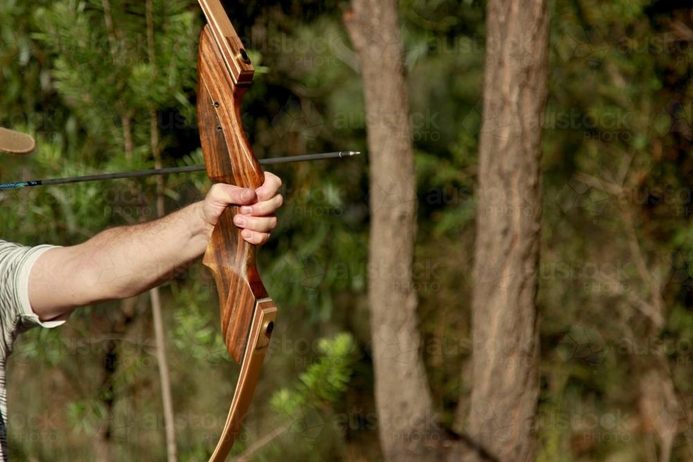 Man shooting an arrow with a wooden takedown recurve bow - Australian Stock Image