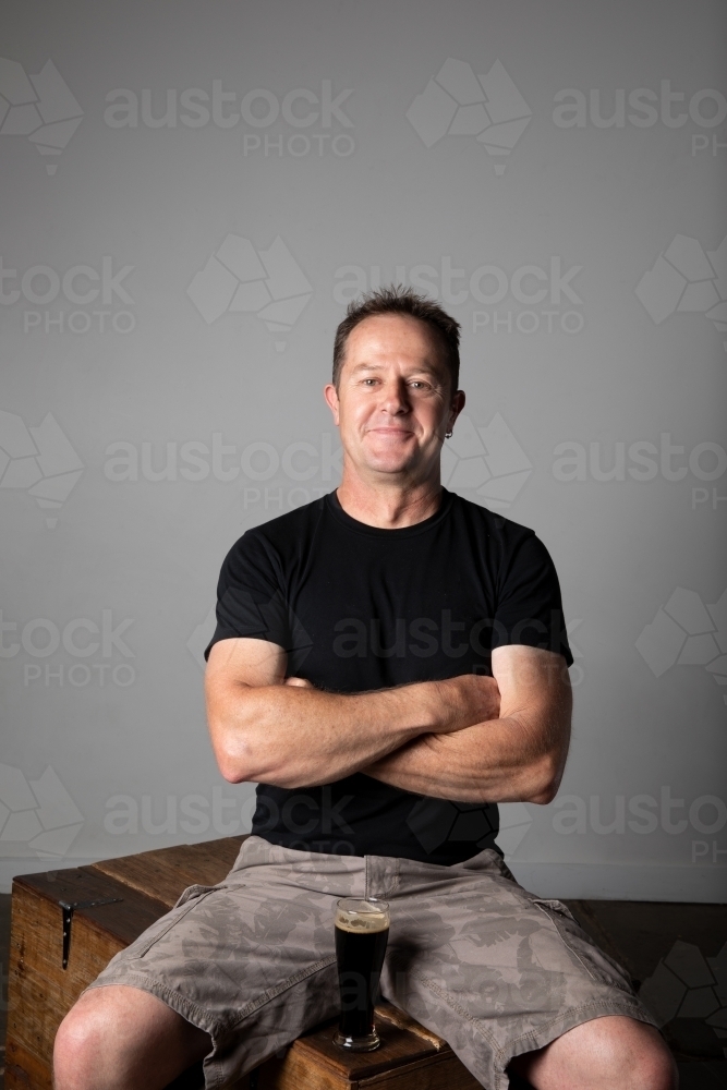 Man sitting, arms folded, relaxed and happy - Australian Stock Image
