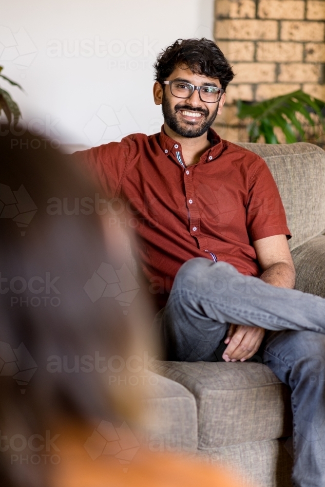 man sitting on couch talking with his partner - Australian Stock Image