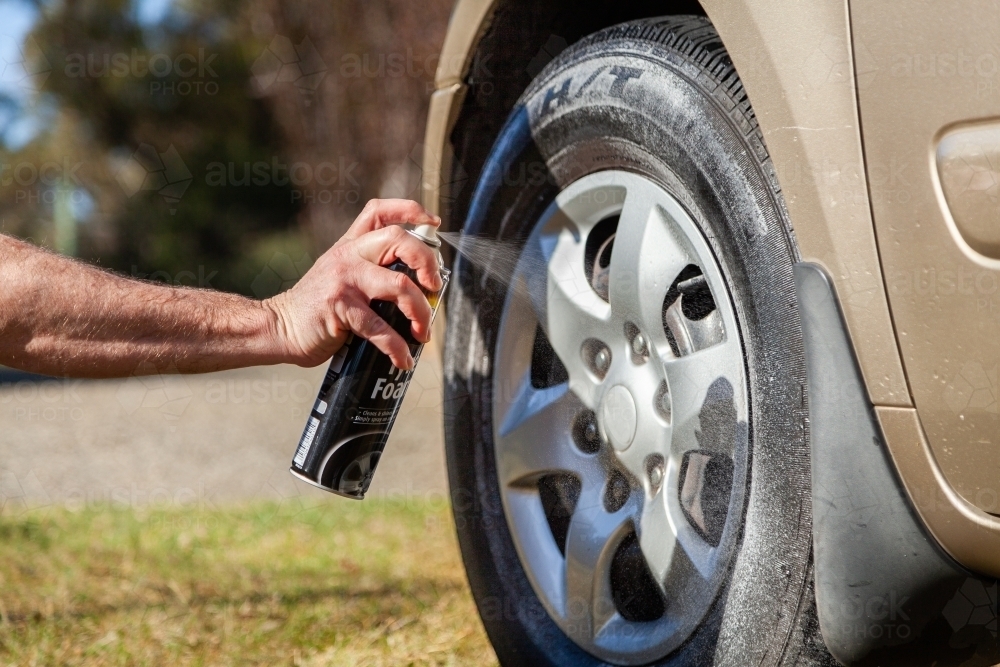 Image of Man spraying tyre foam on car wheel Austockphoto