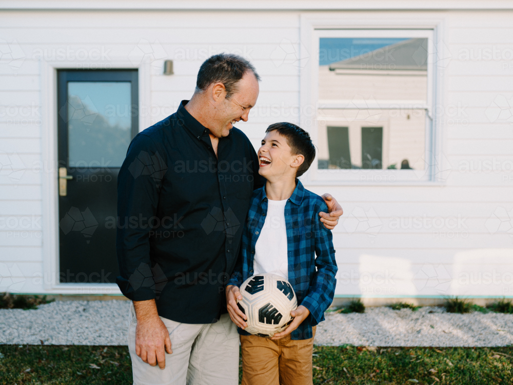 Man standing beside a young boy holding a soccer ball. - Australian Stock Image