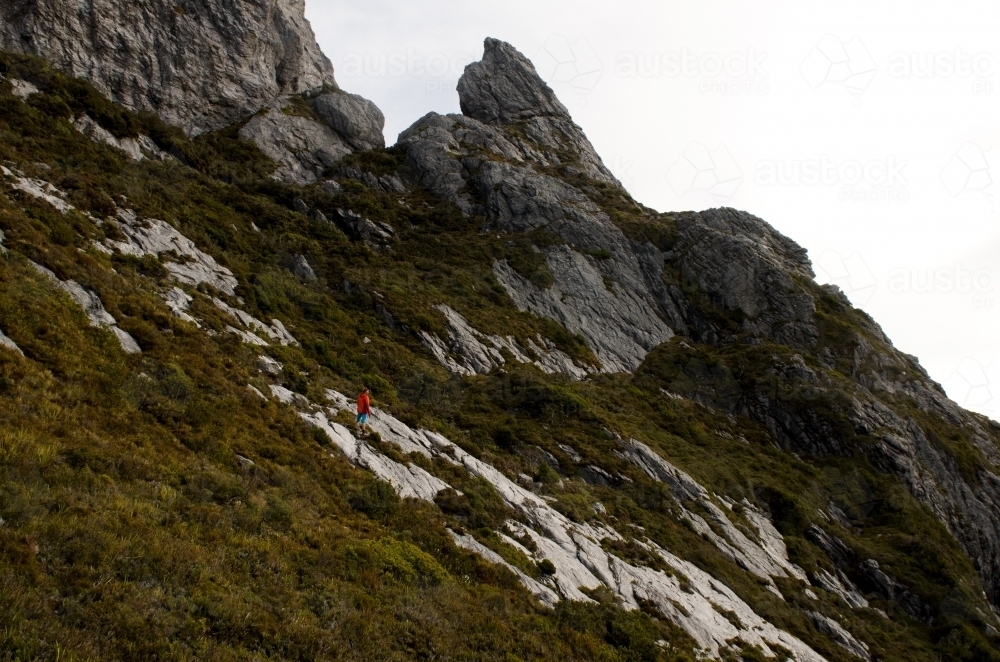 Man standing halfway up a mountain slope - Australian Stock Image