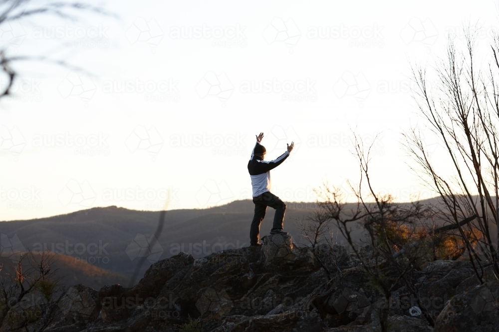 Man standing looking out over mountains on sunset - Australian Stock Image