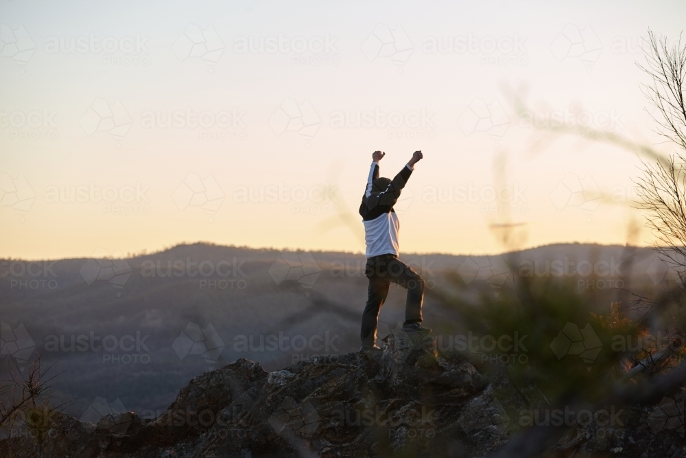 Man standing looking out over mountains on sunset - Australian Stock Image