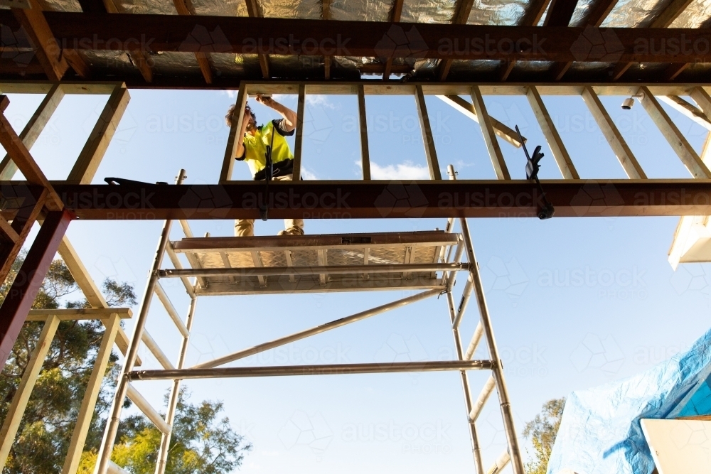Man standing on scaffolding, working on a construction site - Australian Stock Image