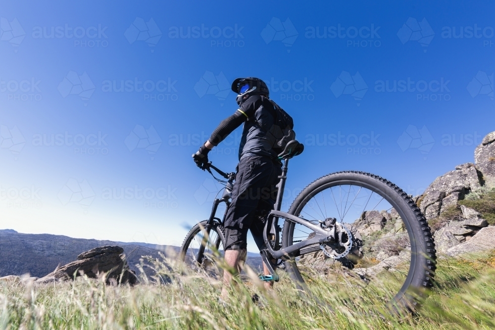 Man standing on top of Mt Kosciuszko with his mountain bike - Australian Stock Image