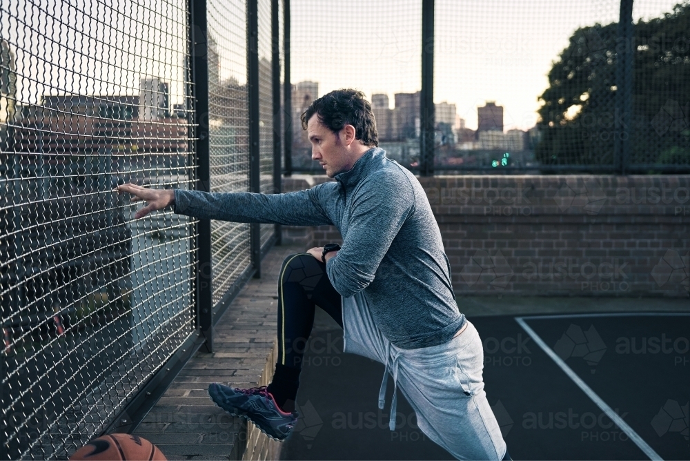 Man stretching on basketball court - Australian Stock Image