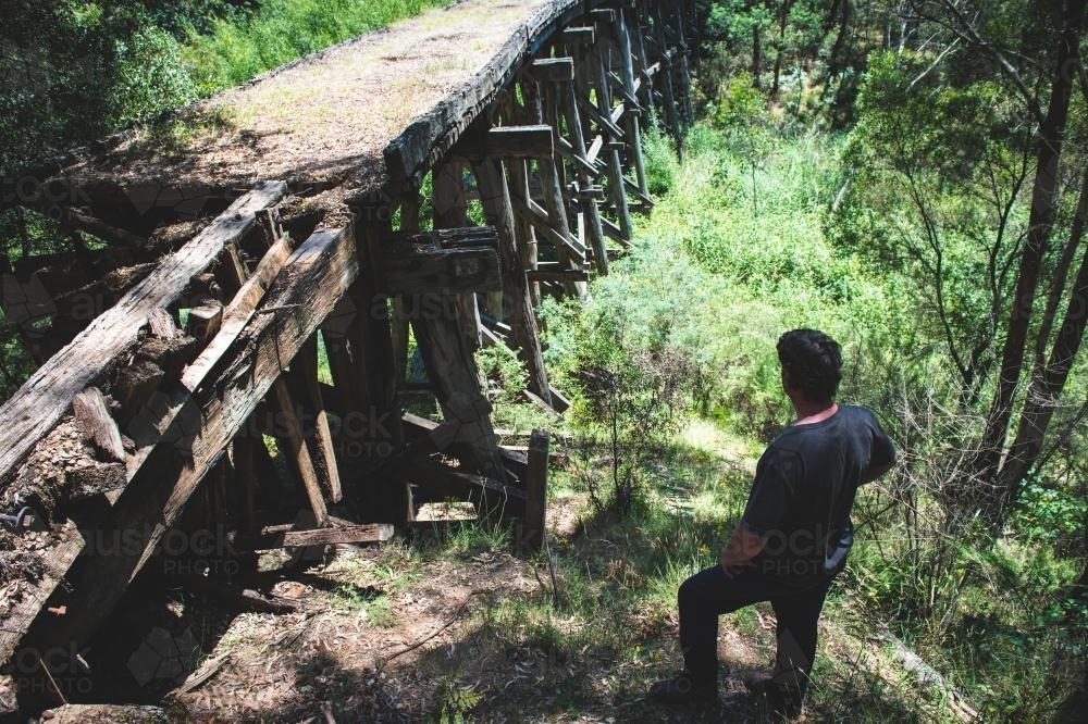 Man surveying old trestle bridge - Australian Stock Image