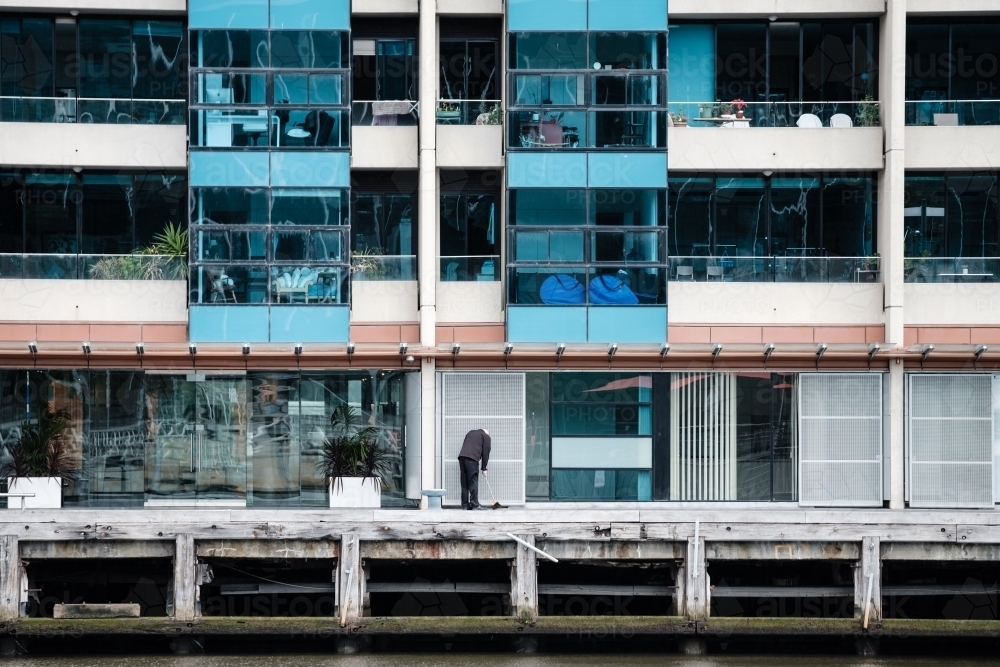 Man Sweeping in Front of Apartment Building on Yarra River - Australian Stock Image