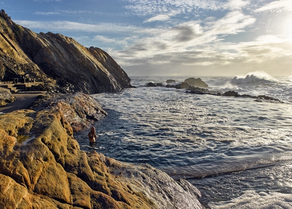 Man swimming at ocean pool in the early morning - Australian Stock Image