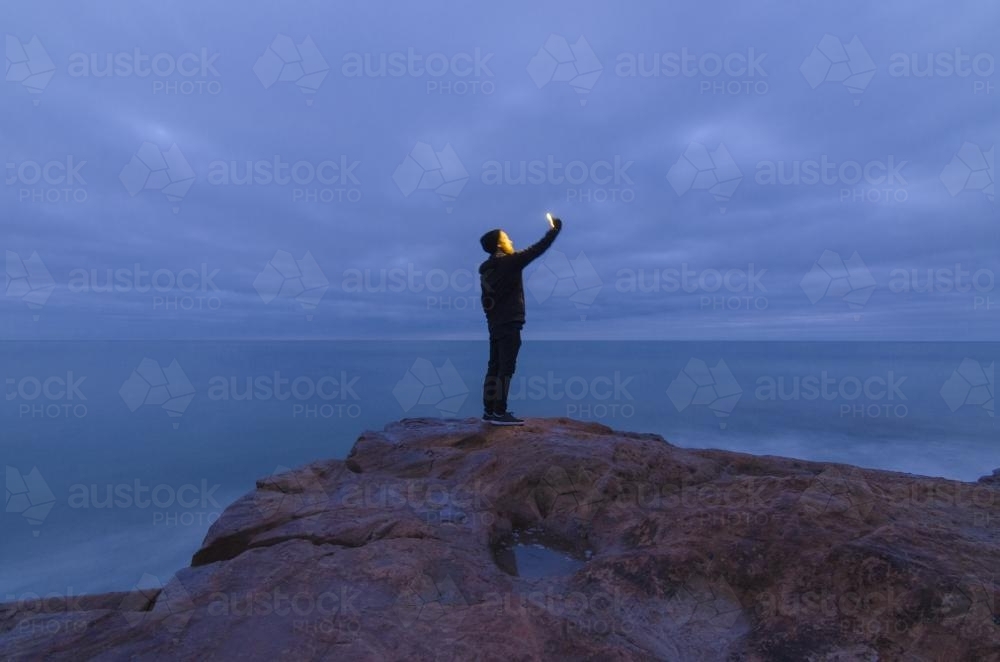 Man Taking Ocean Selfie on Rocks - Australian Stock Image
