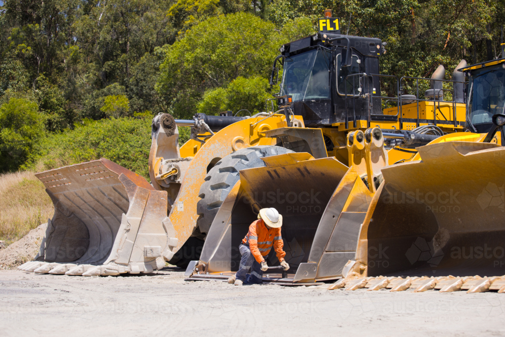 Man tightening the bolts on the bucket of a payloader. - Australian Stock Image