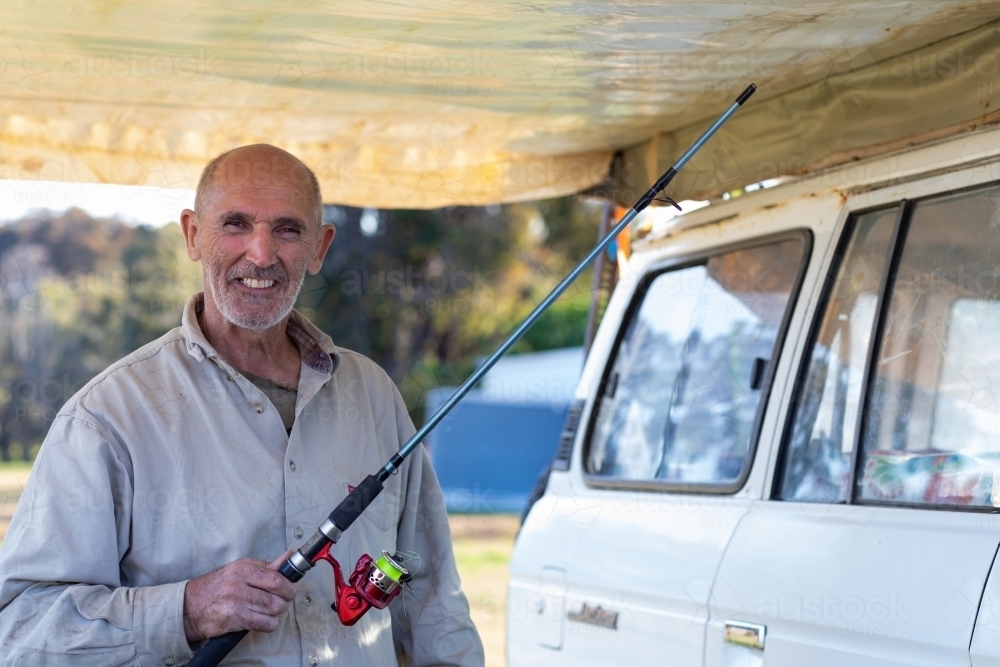 man under awning with fishing rod - Australian Stock Image