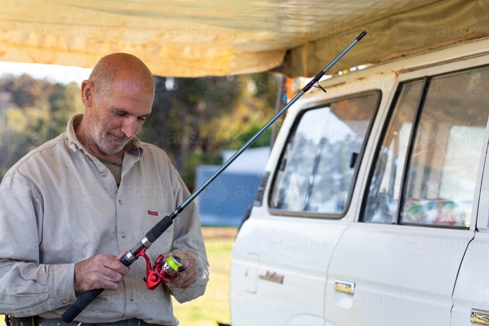 man under awning with fishing rod - Australian Stock Image