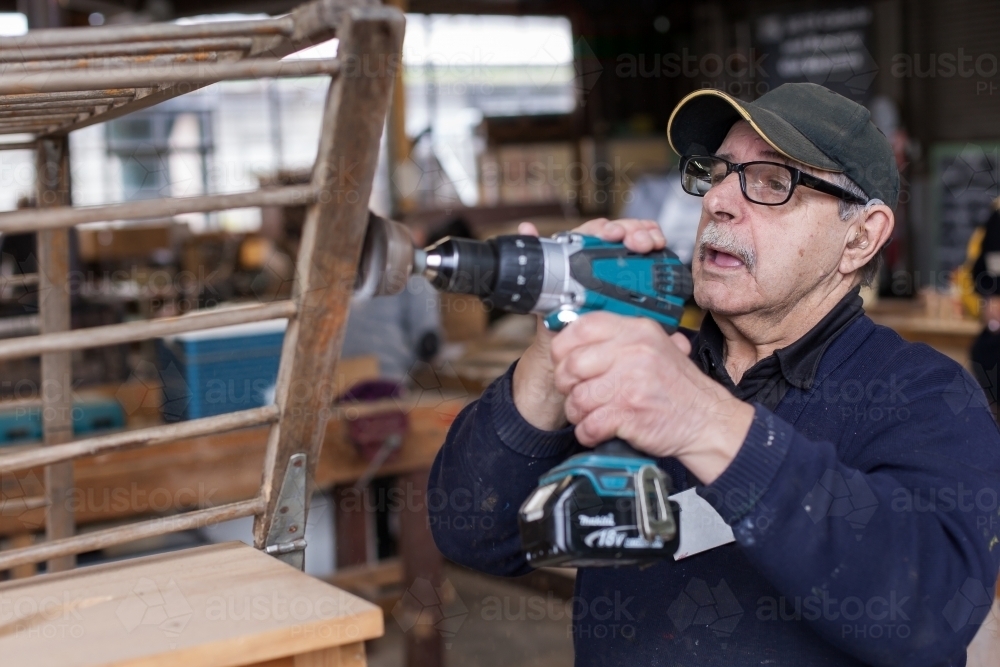 Man using a drill at a men's shed - Australian Stock Image