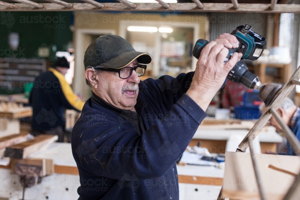 Man using a drill at a Men's shed - Australian Stock Image