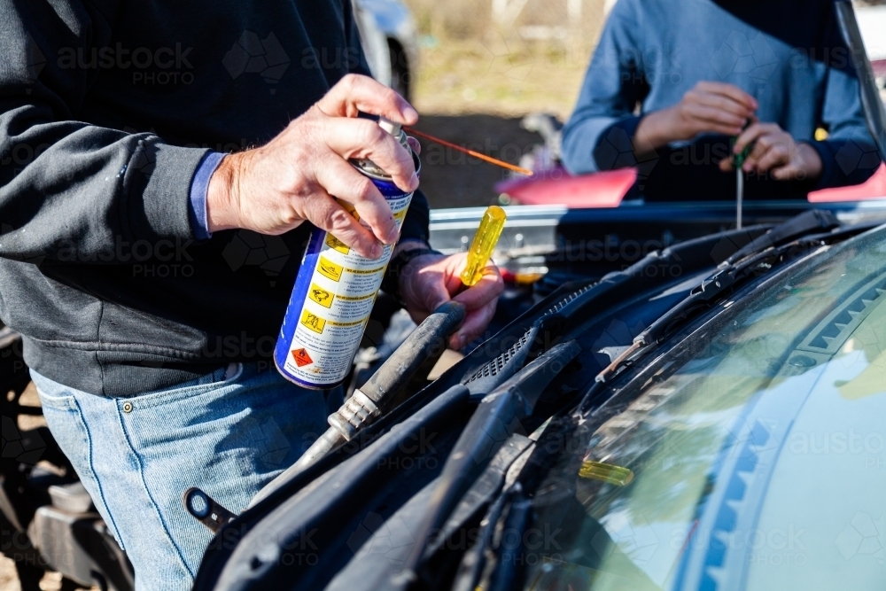 Man using grease to pull apart smashed car for parts - Australian Stock Image