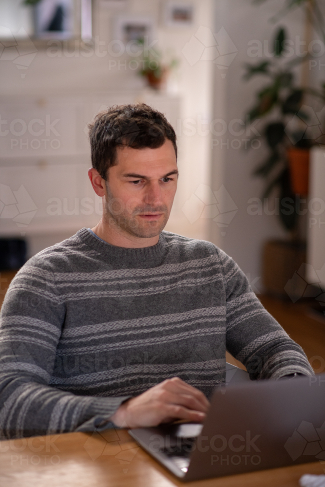Image of man using laptop at home - Austockphoto