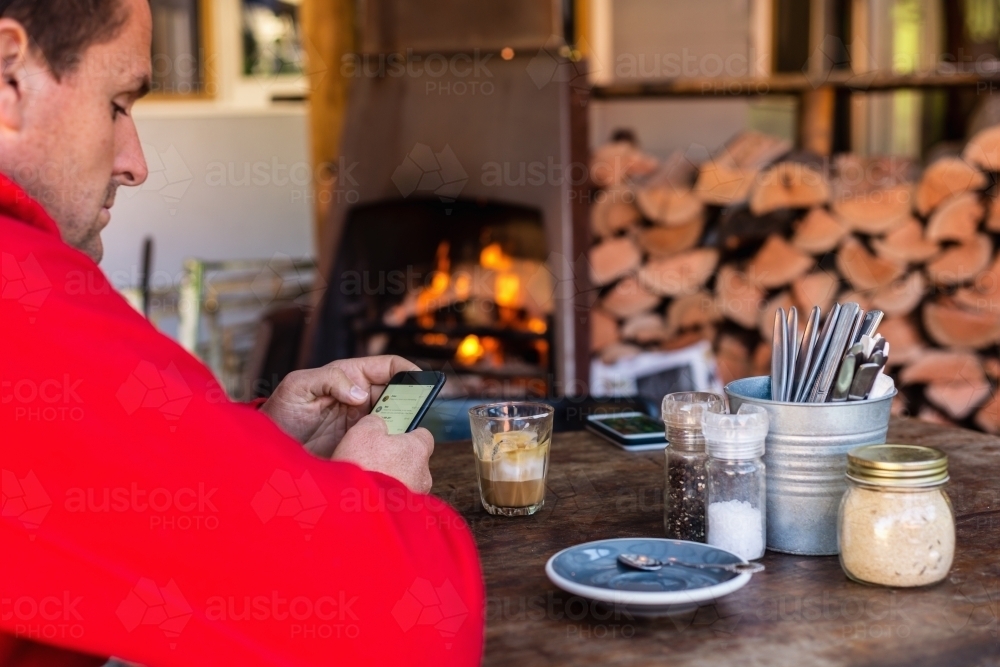 man using phone in cafe whilst on holidays - Australian Stock Image