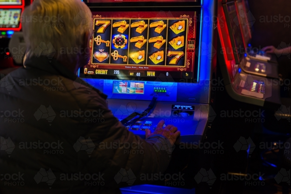 Image of man using slot machine - Austockphoto