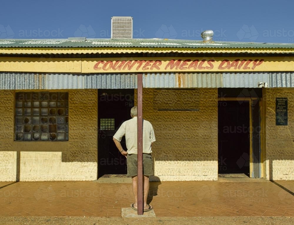 Man waiting standing outside Tennant Creek Hotel - Australian Stock Image