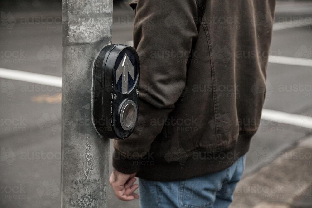 Man waiting to cross pedestrian crossing at traffic lights - Australian Stock Image