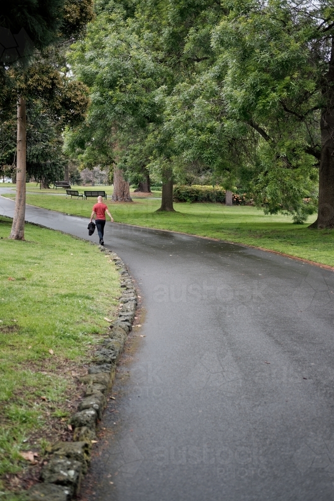 Man walking away in Melbourne Gardens - Australian Stock Image