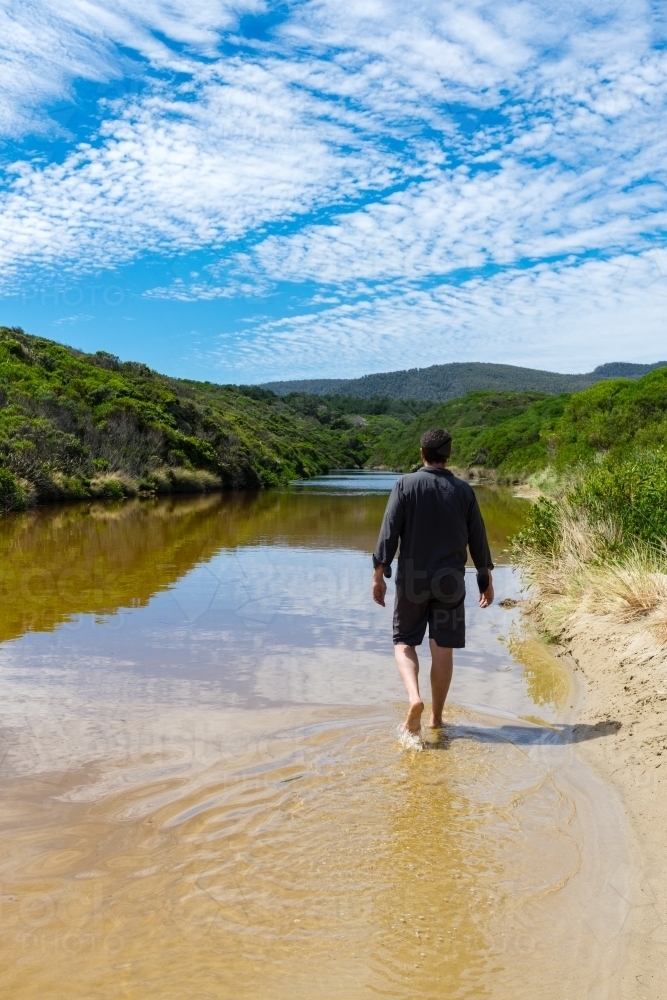 man walking in a fresh water creek by the ocean - Australian Stock Image