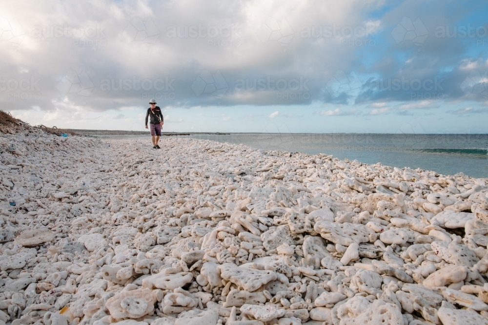 Man walking on a coral beach on a coral island - Australian Stock Image