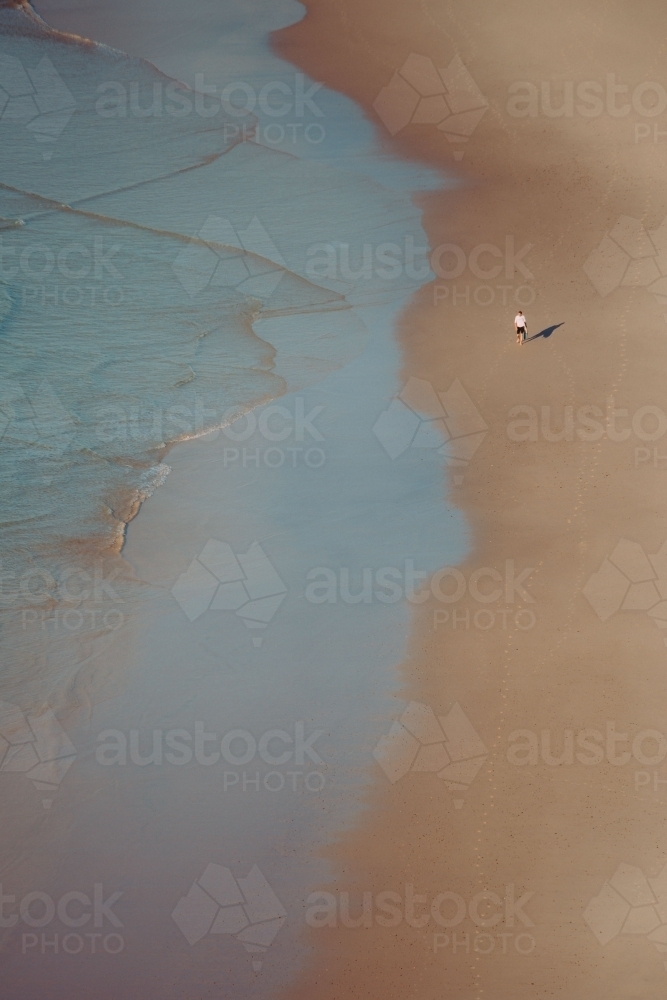 Man walking on a deserted beach - Australian Stock Image