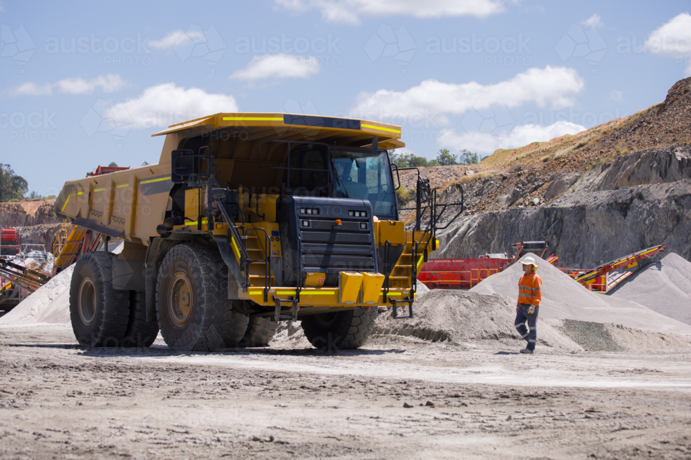 Man walking towards the dump truck with massive wheels. - Australian Stock Image