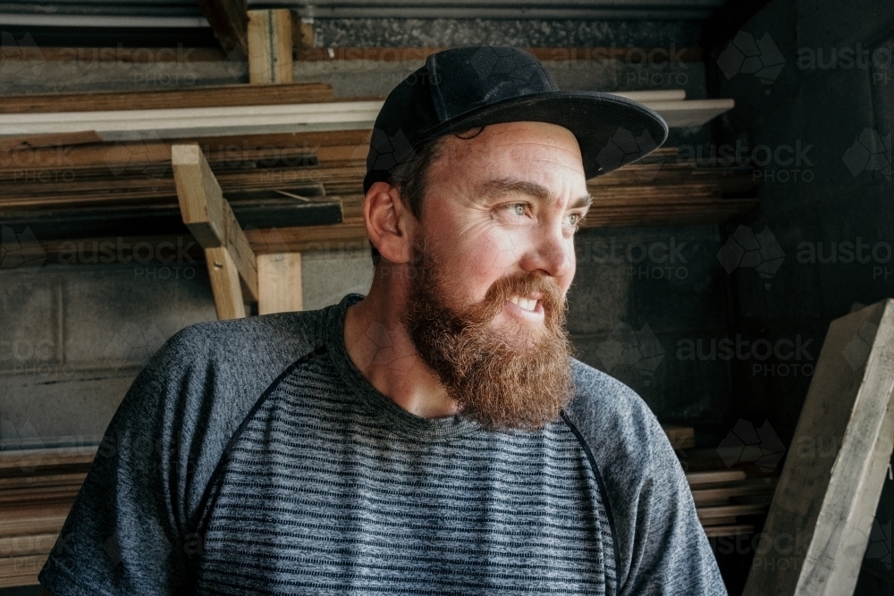 Man wearing a cap looks sideways in his work shop. - Australian Stock Image