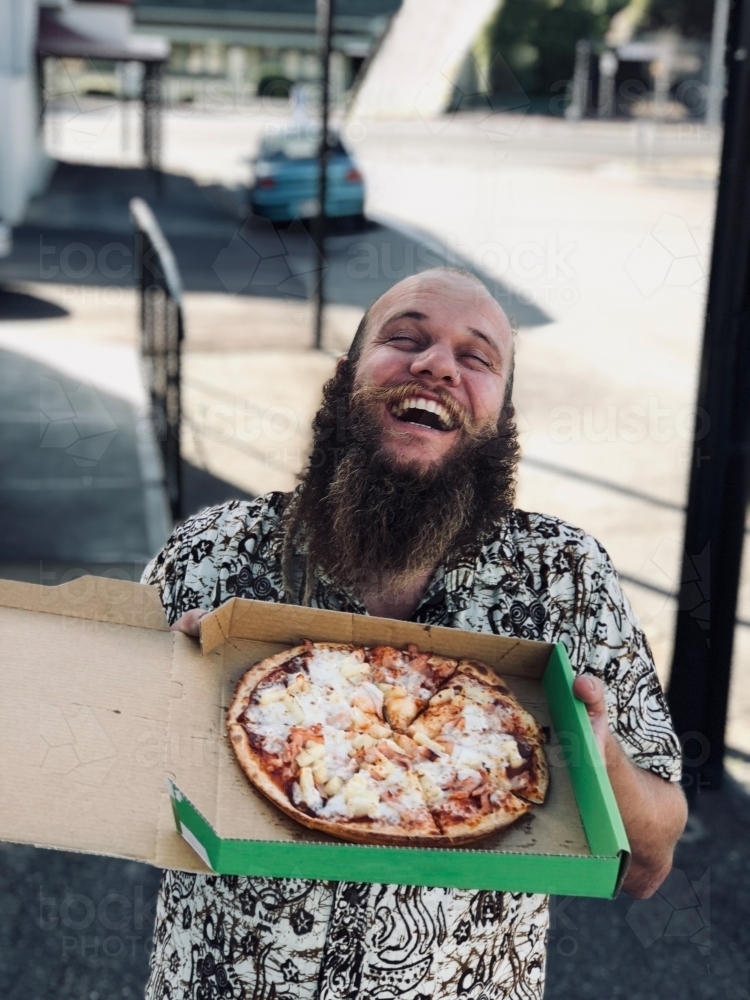 Man with a big smile holding up a pizza - Australian Stock Image