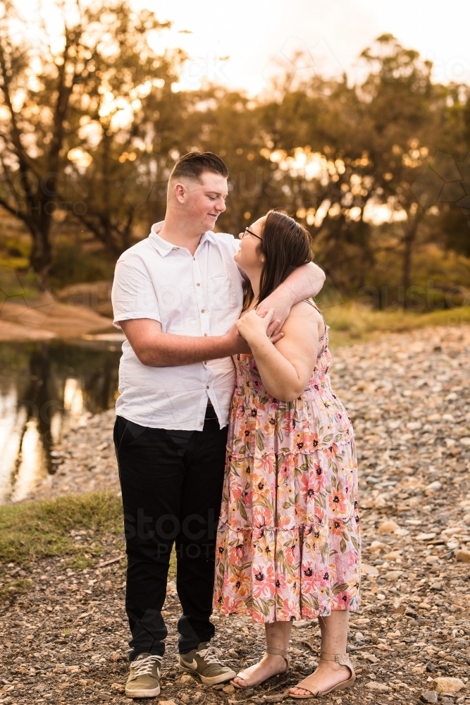 Man with arms around girlfriends shoulders looking at each other in love - Australian Stock Image