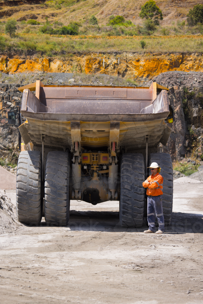 Man with arms crossed standing behind the hauler truck with massive wheels. - Australian Stock Image