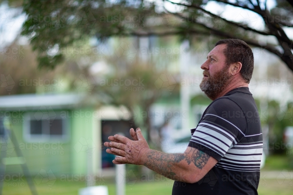 Man with beard and tattoos side on outdoors - Australian Stock Image